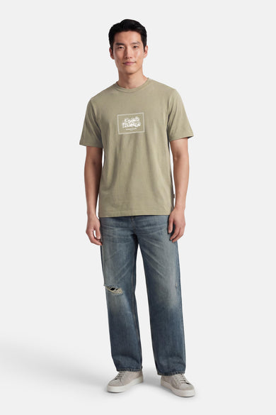 Groen T-shirt met korte mouwen van ORIGINALS BY JACK & JONES met een grafische print op de voorkant, gedragen met een lichtblauwe spijkerbroek.