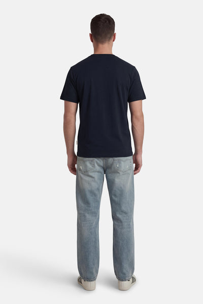 Blauwe T-shirt met korte mouwen van ORIGINALS BY JACK & JONES, gedragen met een verbleekte spijkerbroek en sneakers. Achtergezicht.