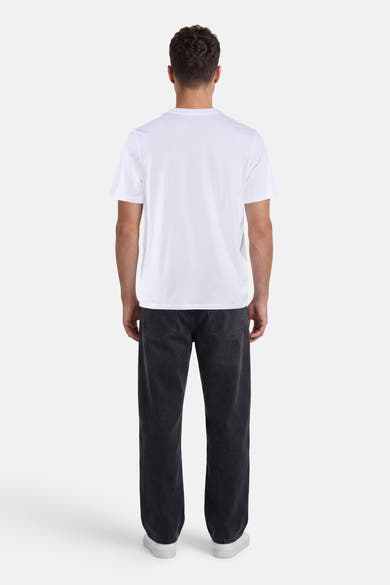 T-shirt blanc à manches courtes de ORIGINALS BY JACK & JONES, porté de dos avec un jean foncé et des baskets blanches.