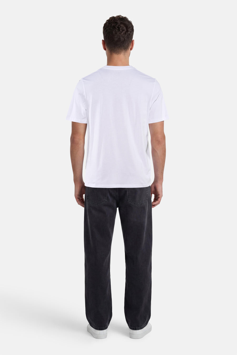 T-shirt blanc à manches courtes de ORIGINALS BY JACK & JONES, porté de dos avec un jean foncé et des baskets blanches.