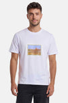 T-shirt blanc d'ORIGINALS BY JACK & JONES avec un motif de timbre-poste représentant un phare et l'inscription "Somewhere.", porté par un homme en jean noir.