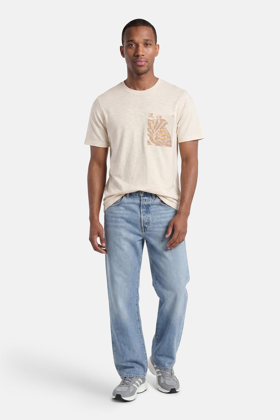Gele T-shirt van PREMIUM by JACK & JONES met bruin en oranje geborduurd borstzakje, gedragen met een spijkerbroek en sneakers.