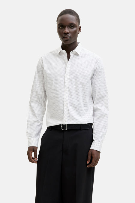 Chemise à manches longues blanche de PREMIUM by JACK & JONES, avec un motif discret, portée avec un pantalon noir et une ceinture.