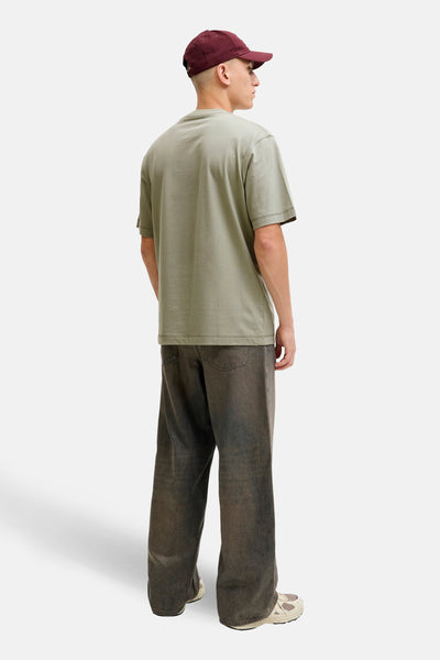 Groen T-shirt met korte mouwen van ORIGINALS BY JACK & JONES, gedragen met een donkere wijde broek en een bordeauxrode pet.