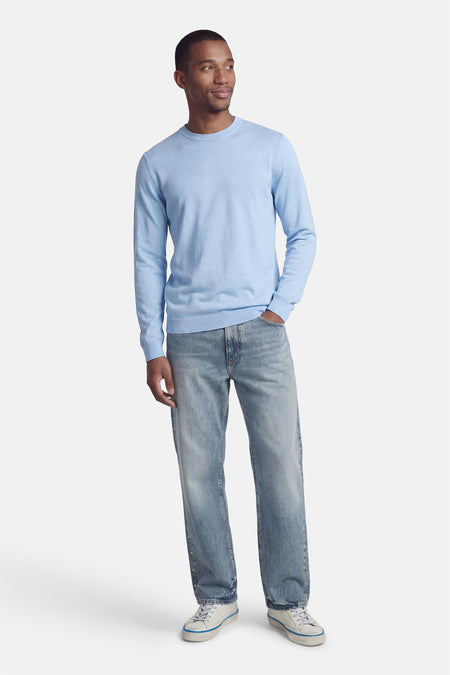 Blauwe trui met ronde hals van PREMIUM by JACK & JONES, gedragen met een verbleekte spijkerbroek en witte sneakers.