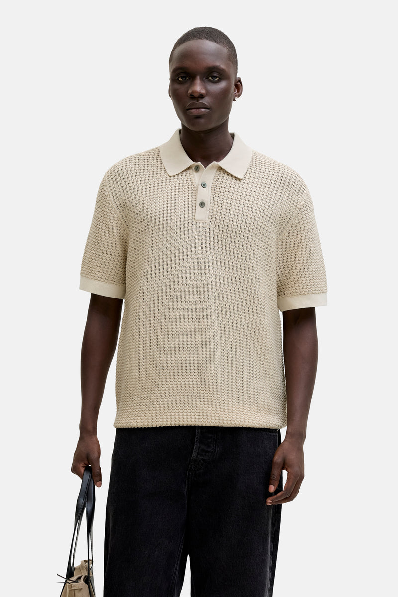 Polo beige en maille de PREMIUM by JACK & JONES, porté avec un jean noir et un sac à main.