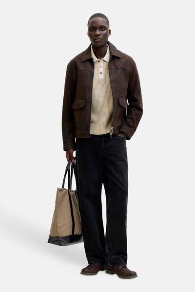 Polo beige, de PREMIUM by JACK & JONES, porté avec une veste en cuir marron, un jean noir et des chaussures marron.