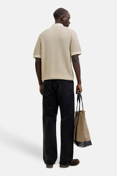 Polo beige en maille, de PREMIUM by JACK & JONES, porté avec un jean noir ample et un sac.