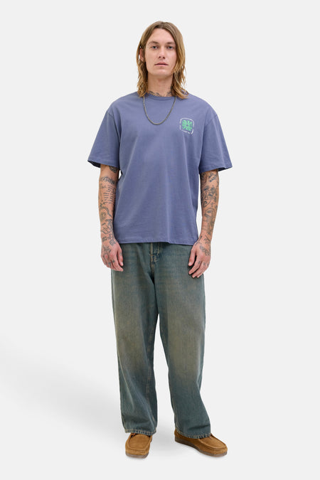 Blauw T-shirt met korte mouwen van Originals by Jack & Jones met een opdruk op de borst, gedragen met een bruine broek en schoenen.