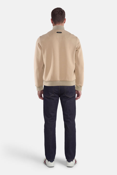 Veste beige de PREMIUM by JACK & JONES, vue de dos, portée avec un jean bleu foncé et des baskets blanches.