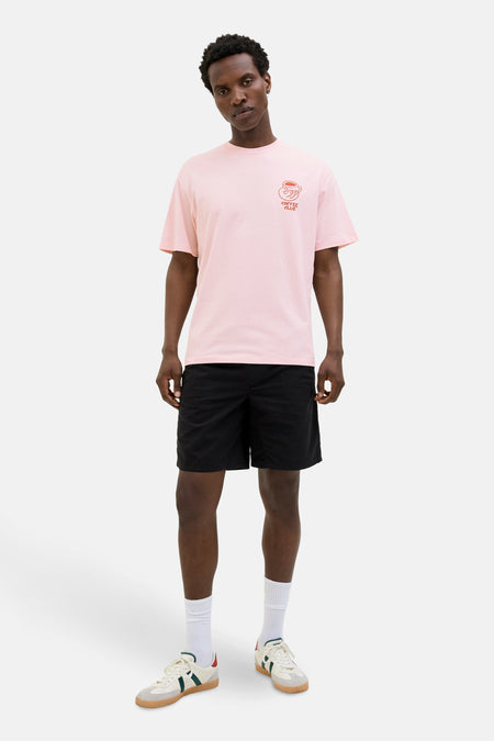 T-shirt rose à manches courtes de ORIGINALS BY JACK & JONES, avec motif imprimé, porté avec un short noir et des chaussures de sport.