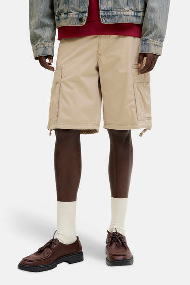 Short beige de JACK & JONES, coupe décontractée avec poches cargo, porté avec chaussettes blanches et chaussures en cuir marron.