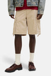 Short beige de JACK & JONES, coupe décontractée avec poches cargo, porté avec chaussettes blanches et chaussures en cuir marron.