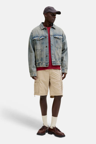 Short beige de JACK & JONES porté avec une veste en jean, un t-shirt rouge et des chaussures marron.