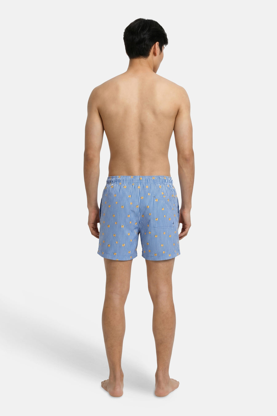 Blauwe zwembroek van JACK & JONES JEANS INTELLIGENCE met witte verticale strepen en oranje vierkante patronen, gedragen door een man, achtergezicht.