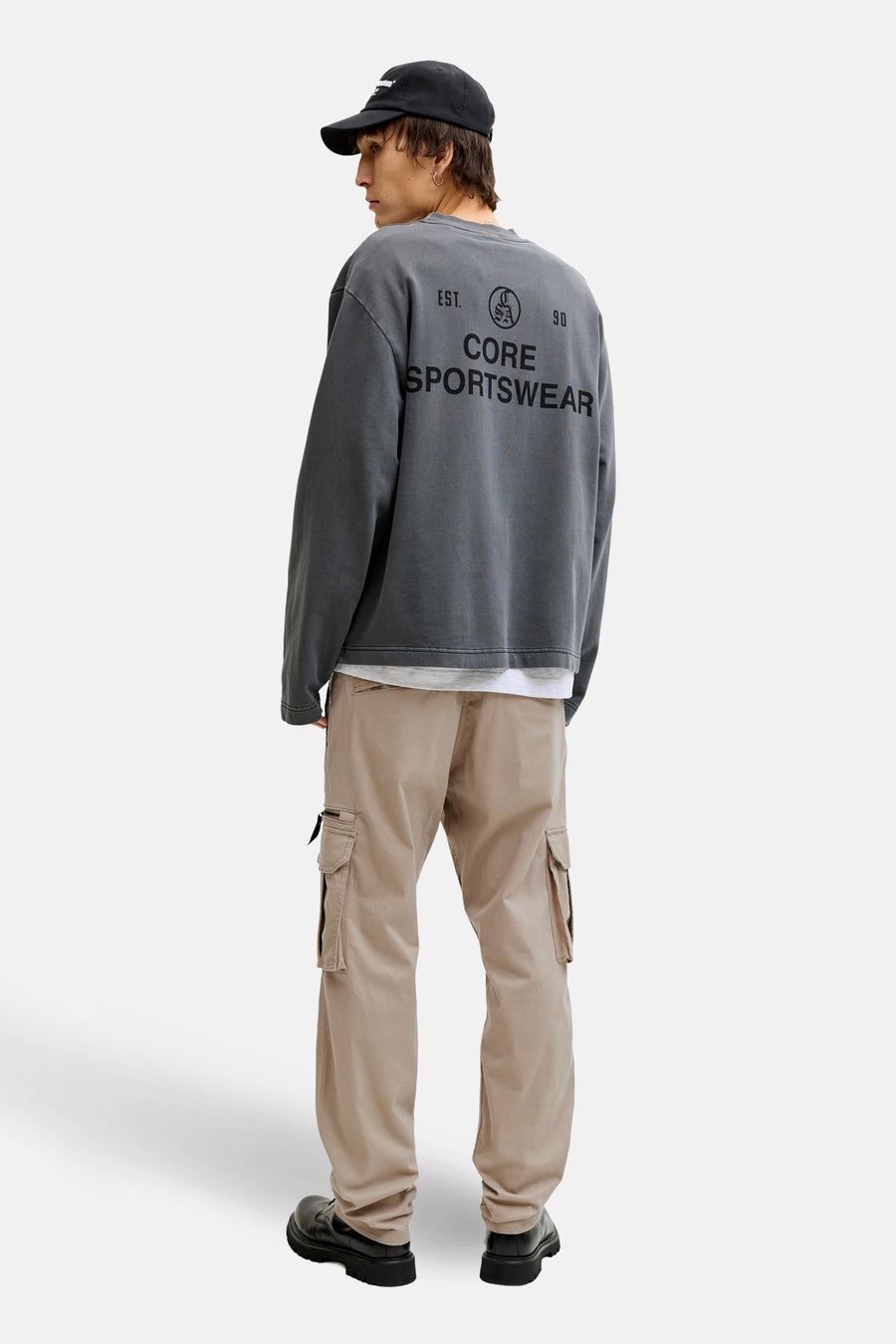 Beige cargobroek van JACK & JONES, gedragen met een grijs bedrukt sweatshirt en dikke zwarte schoenen.