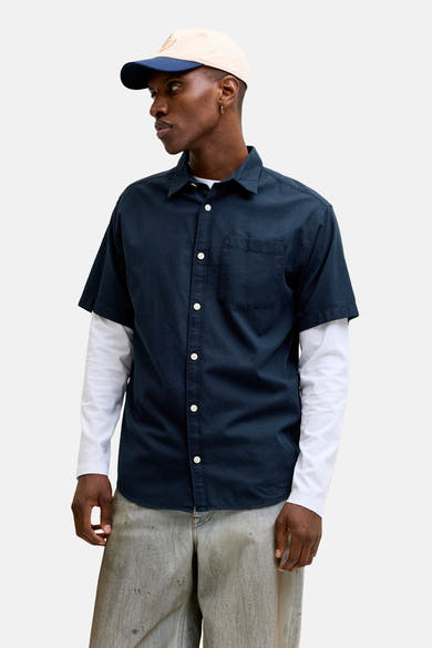 Blauw overhemd met korte mouwen van JACK & JONES, met subtiele textuur, gedragen over een wit T-shirt met lange mouwen en een casual broek.