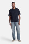 Polo bleu à manches courtes de JACK & JONES avec bordure blanche, porté avec un jean décontracté et des chaussures en daim.