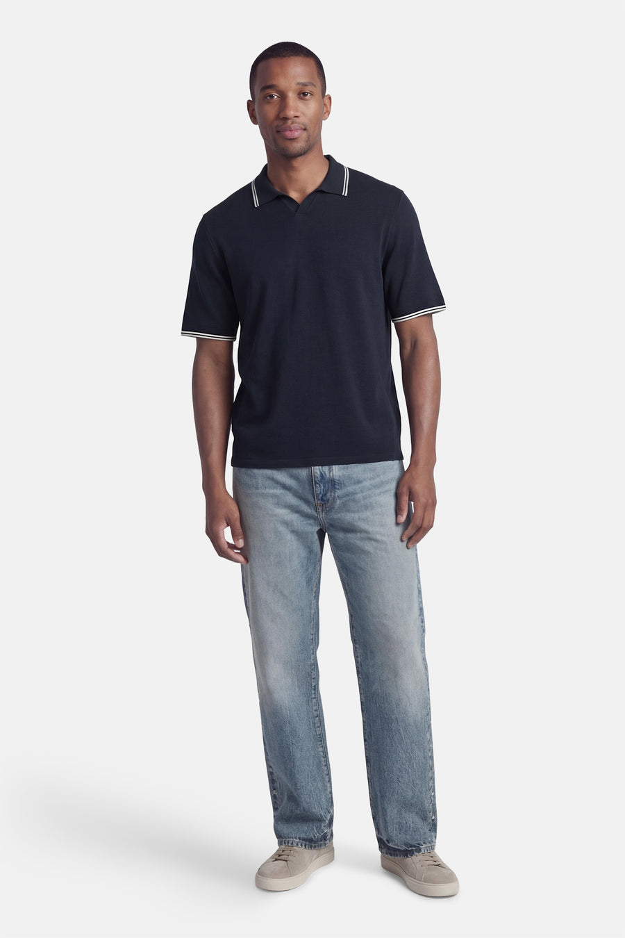 Polo bleu à manches courtes de JACK & JONES avec bordure blanche, porté avec un jean décontracté et des chaussures en daim.
