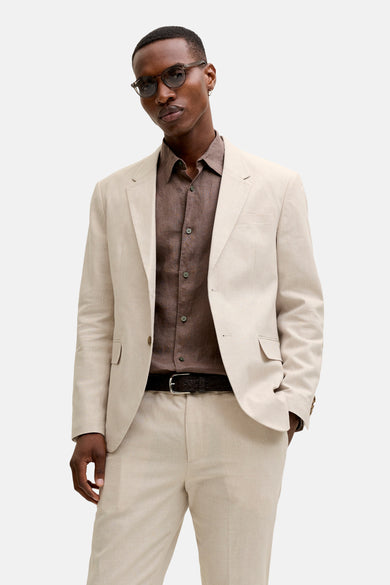 Blazer écru de PREMIUM by JACK & JONES, en tissu léger, porté ouvert avec une chemise marron et un pantalon assorti.