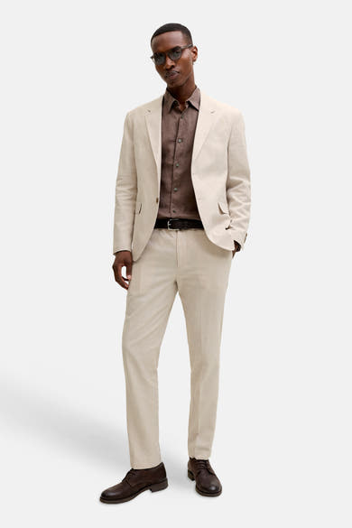 Blazer écru de PREMIUM by JACK & JONES à la texture lin, porté avec une chemise marron et un pantalon assorti.