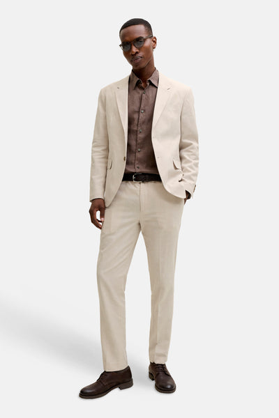 Blazer écru de PREMIUM by JACK & JONES à la texture lin, porté avec une chemise marron et un pantalon assorti.