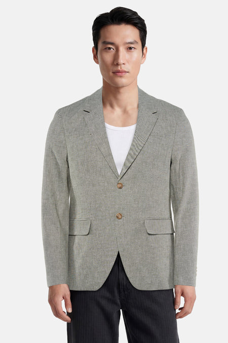 Blazer vert en tissu texturé de PREMIUM by JACK & JONES, à revers crantés, deux boutons et poches plaquées, porté sur un débardeur blanc.
