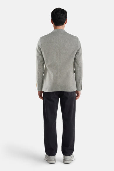 Blazer vert de JACK & JONES, tissé avec boutons aux poignets, porté de dos avec un pantalon côtelé foncé et des baskets.