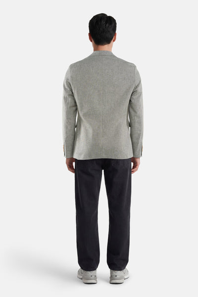 Blazer vert de JACK & JONES, tissé avec boutons aux poignets, porté de dos avec un pantalon côtelé foncé et des baskets.