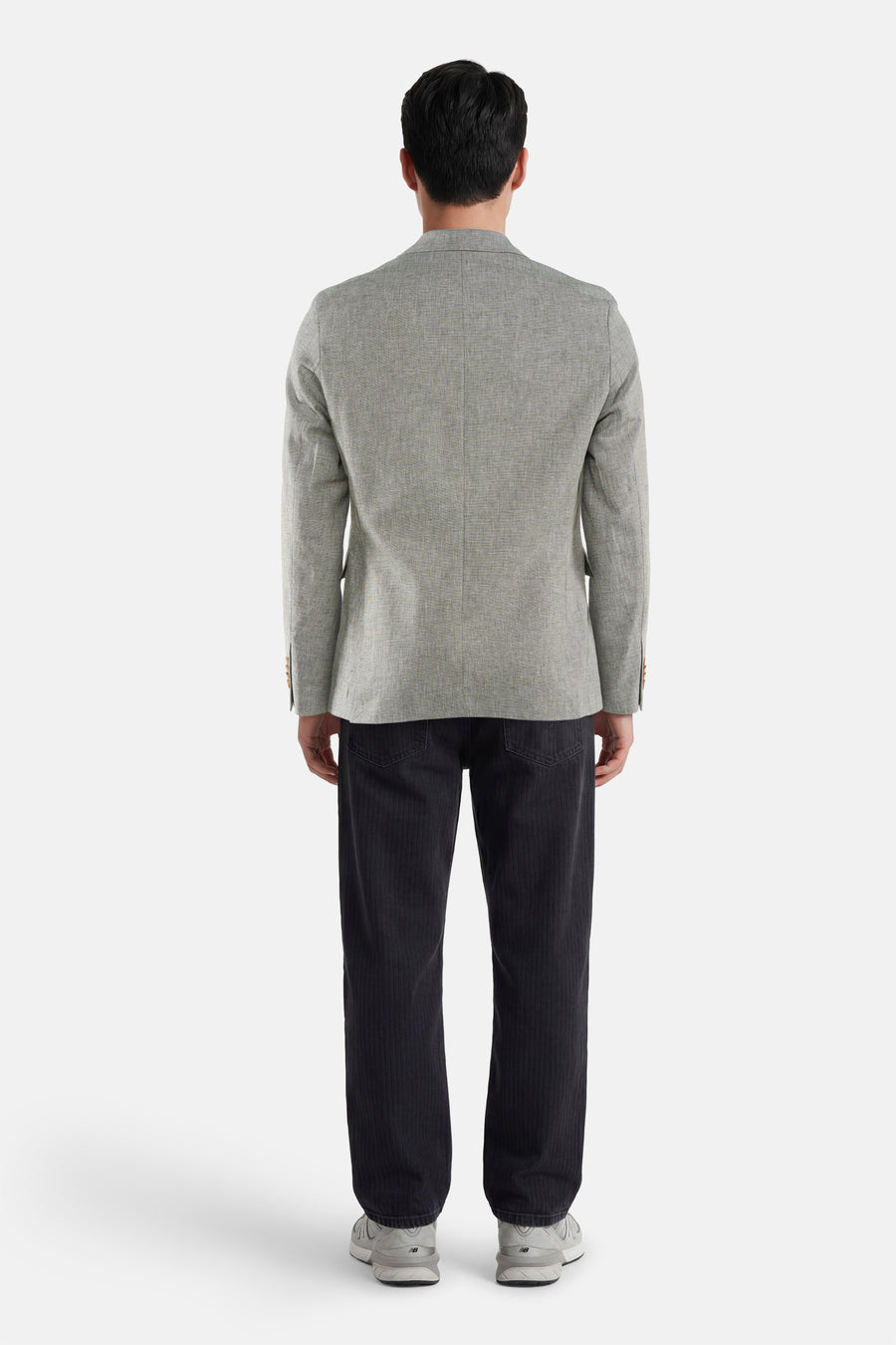Blazer vert de JACK & JONES, tissé avec boutons aux poignets, porté de dos avec un pantalon côtelé foncé et des baskets.