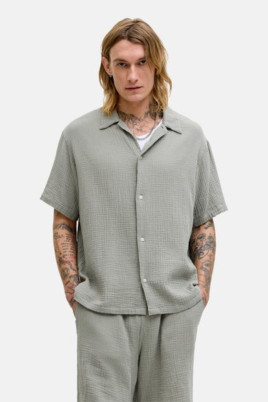 Chemise à manches courtes verte par ORIGINALS BY JACK & JONES, en tissu texturé gaufré, portée ouverte sur un t-shirt blanc.