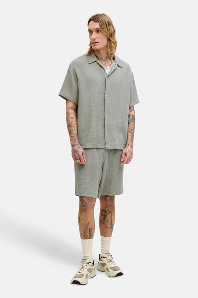 Chemise à manches courtes verte par ORIGINALS BY JACK & JONES, texture gaufrée, portée avec un short assorti et des baskets.