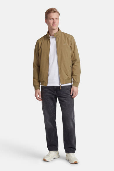 Veste courte beige par ORIGINALS BY JACK & JONES, avec fermeture éclair et poches, portée avec un jean noir et des baskets blanches.