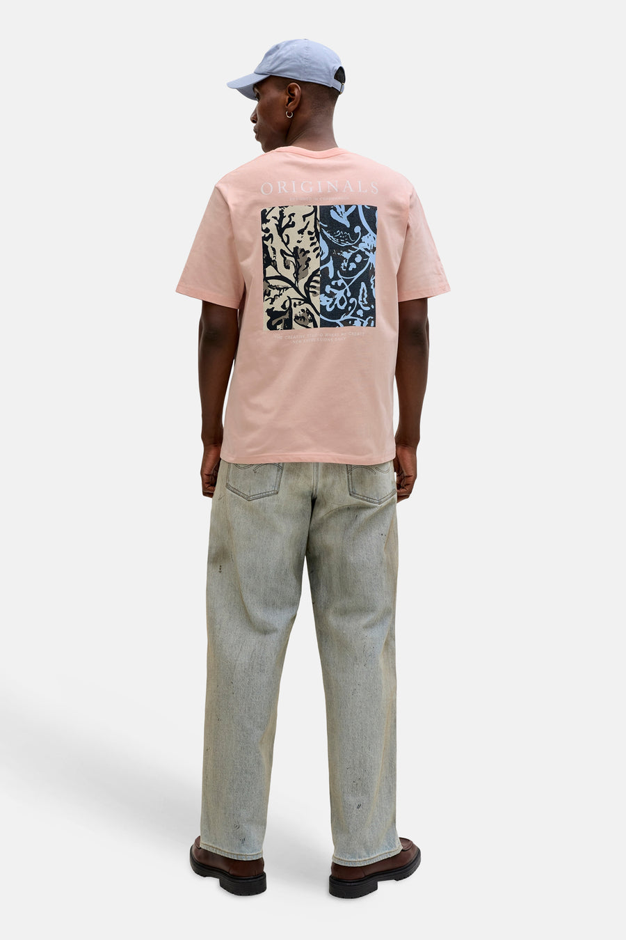 Oranje T-shirt met korte mouwen van ORIGINALS BY JACK & JONES, grafische print op de rug, gedragen met een spijkerbroek en een pet.