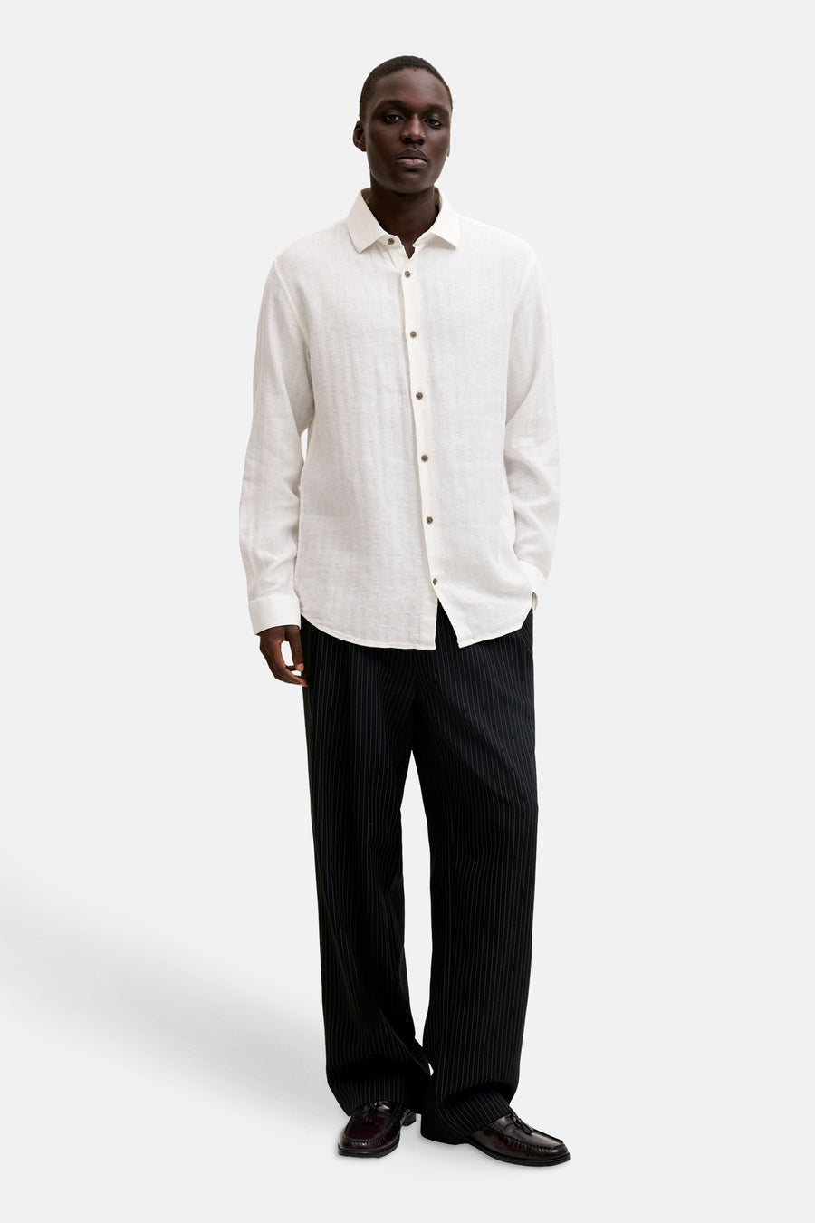 Chemise blanche de PREMIUM by JACK & JONES, en tissu texturé, portée avec un pantalon rayé noir et des mocassins.
