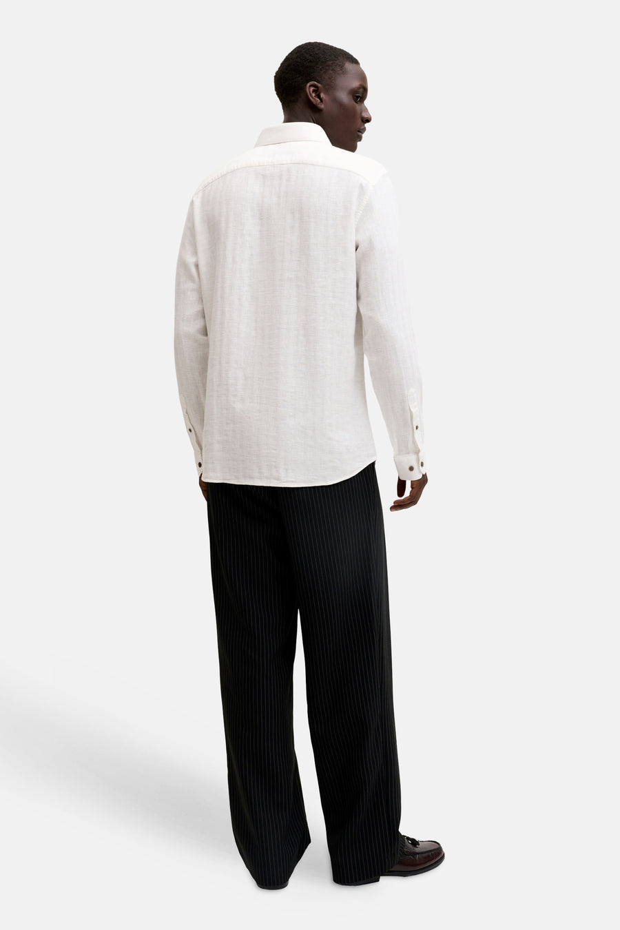 Chemise blanche à manches longues de PREMIUM by JACK & JONES, en tissu texturé, vue de dos sur un homme avec un pantalon rayé noir et des mocassins.