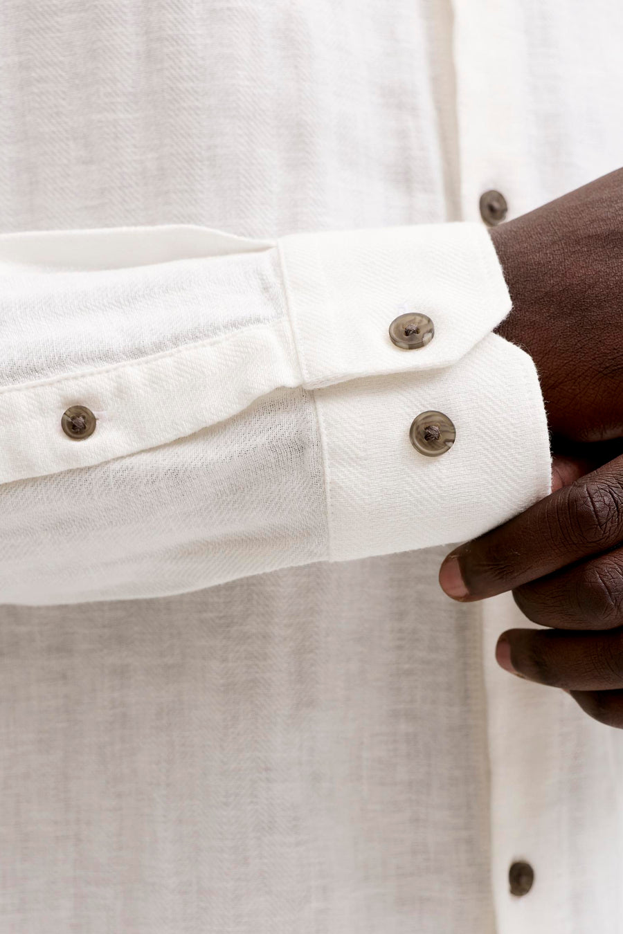 Chemise blanche à manches longues de PREMIUM by JACK & JONES avec motif chevrons, une main ajustant le poignet boutonné.