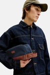 Blauwe toilettas van ACCESSORIES BY JACK & JONES met bruin inzetstuk, gedragen met een spijkerjasje.