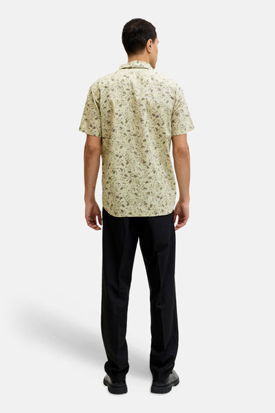 Multikleuren overhemd met korte mouwen van PREMIUM by JACK & JONES, bloemenprint op een beige achtergrond, gedragen met een zwarte broek.