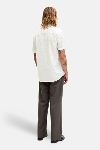 Chemise blanche à manches courtes de PREMIUM by JACK & JONES, motif discret, portée avec un pantalon gris.