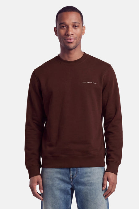 Sweat col O marron de PREMIUM by JACK & JONES, avec logo brodé blanc sur poitrine, porté par un homme en jeans bleu clair, vue frontale.