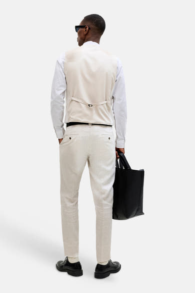 Ecru gilet van PREMIUM by JACK & JONES, van achteren gedragen met verstelbare band, over wit overhemd en lichte broek.