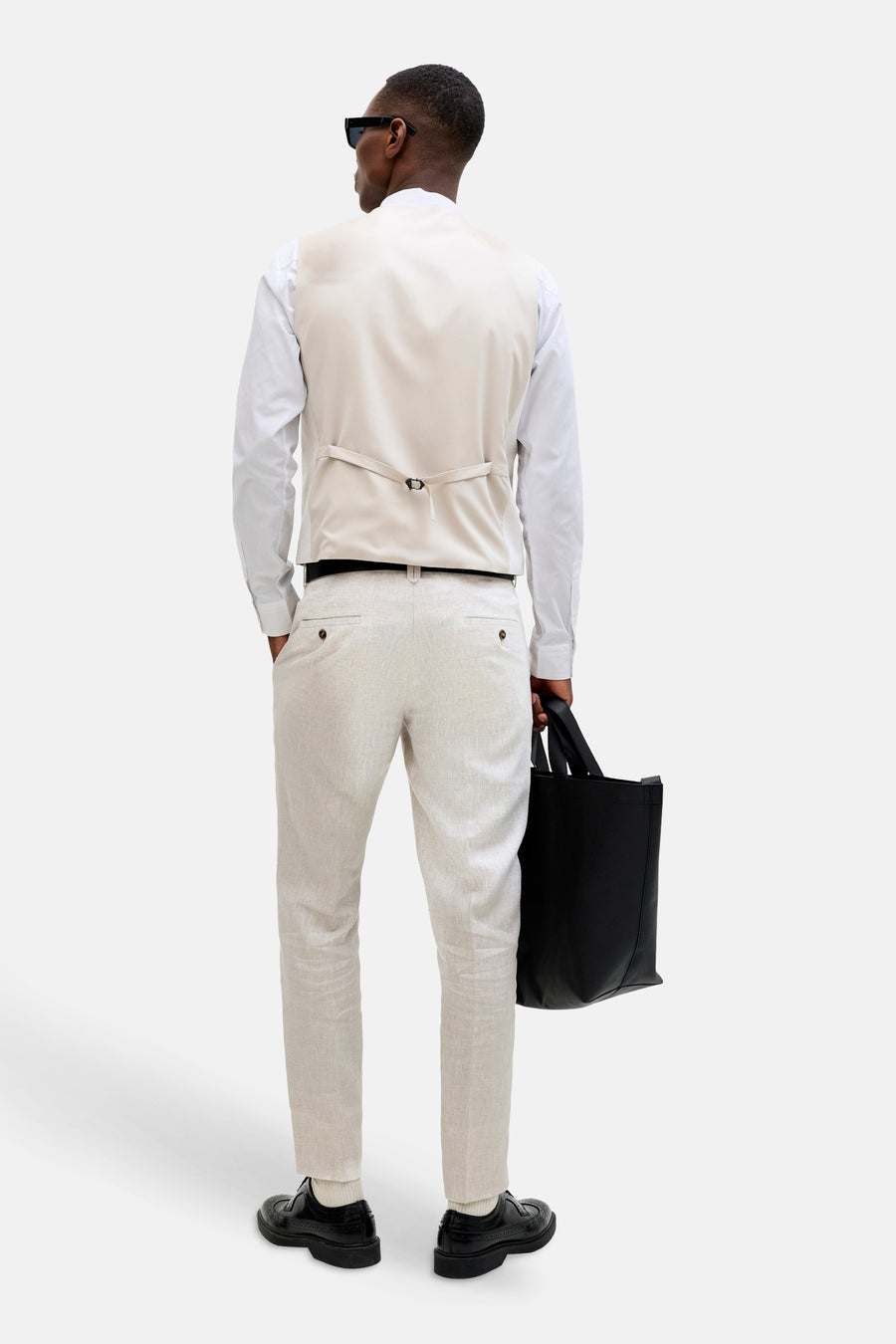 Ecru gilet van PREMIUM by JACK & JONES, van achteren gedragen met verstelbare band, over wit overhemd en lichte broek.