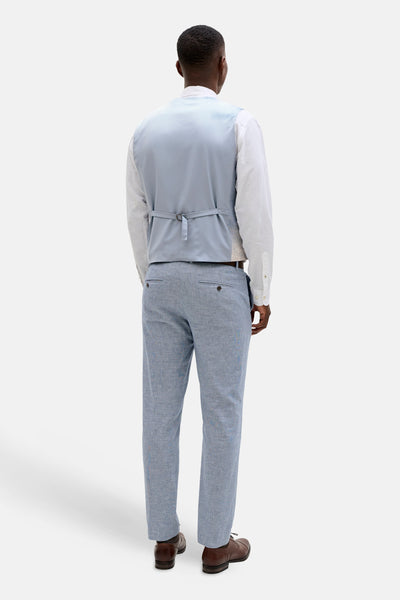 Light blue satin gilet with back tie closure, worn over white shirt and paired with textured gray trousers, back view.