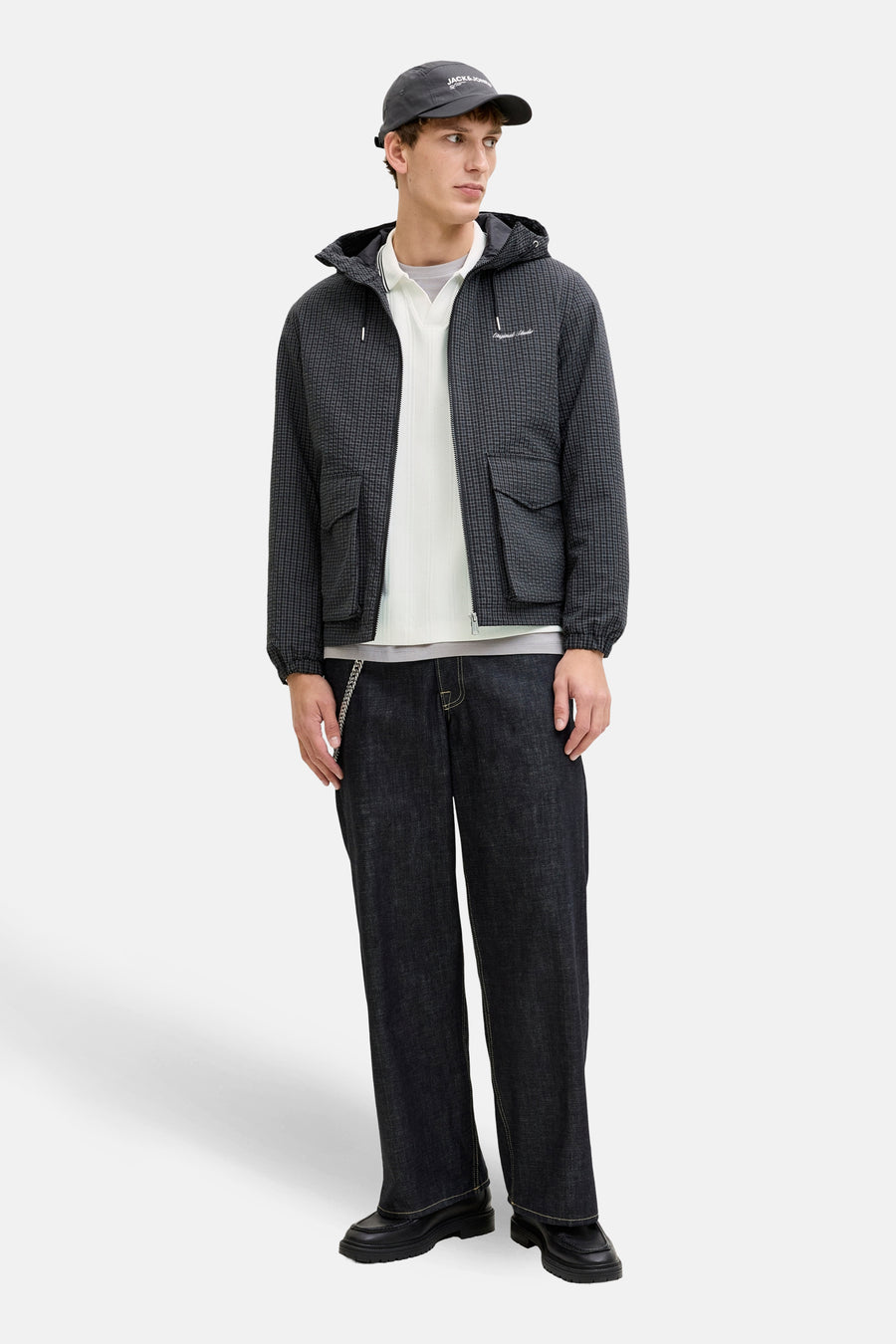Sweat-shirt col rond blanc de Originals by Jack & Jones, porté avec une veste à carreaux et un pantalon foncé.