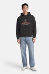 Zwarte hoodie van PREMIUM by JACK & JONES, met print en gedragen met een blauwe jeans en witte schoenen.