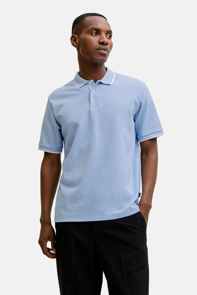 Polo bleu à manches courtes par PREMIUM by JACK & JONES, avec col et bordures blanches, porté avec un pantalon noir.