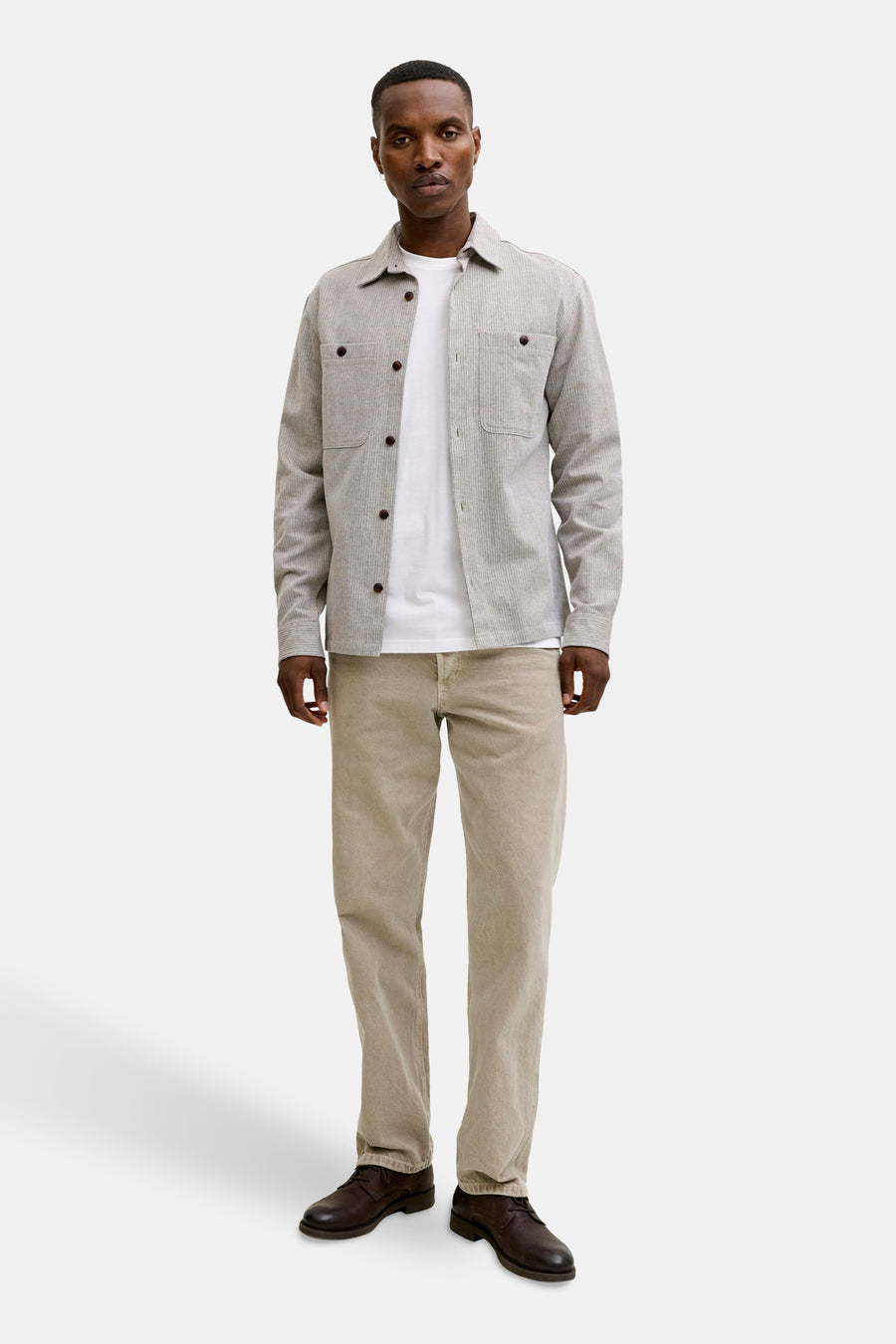 T-shirt blanc à manches courtes de PREMIUM BLUE by JACK & JONES porté avec une chemise et un pantalon beige.