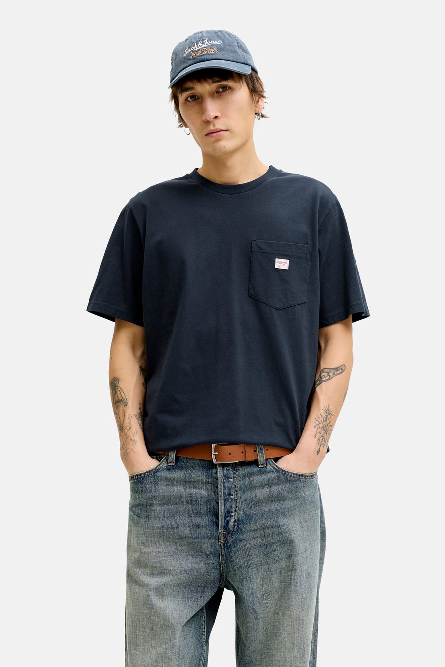 T-shirt à manches courtes bleu PREMIUM BLUE van JACK & JONES, gedragen met een camelkleurige jas, een wijde jeans en bootschoenen.