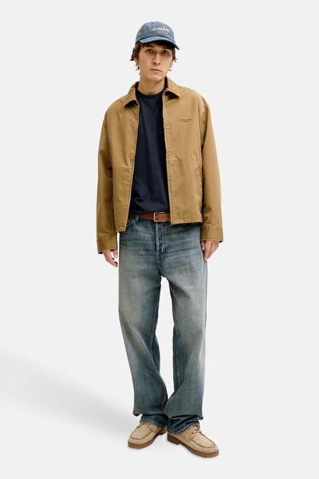 T-shirt à manches courtes bleu PREMIUM BLUE par JACK & JONES, porté avec une veste camel, un jean ample et des chaussures bateau.